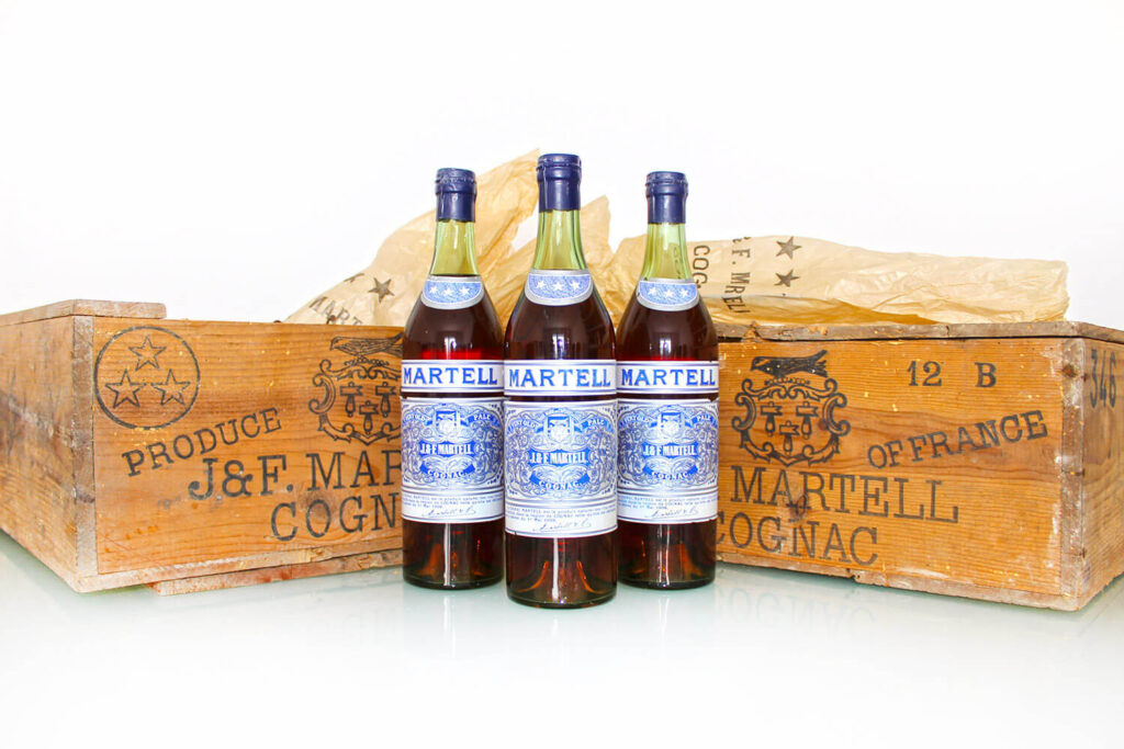 3 Martell Flaschen neben Kisten